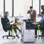 Xerox® Série VersaLink® C7100, imprimante multifonctions couleur en situation au travail Equipe de travail dans un bureau avec des papiers imprimés et l'imprimante multifonctions couleur Xerox® Série VersaLink C7100